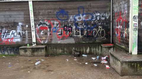 Mit Graffiti besprühte Mauerecke mit achtlos entsorgtem Müll