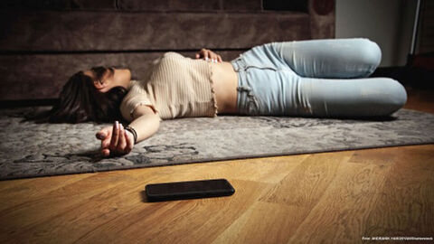 Mädchen am Boden liegend, daneben Smart-Phone