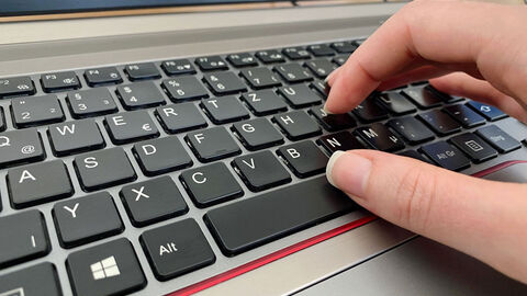 Hand tippt auf Tastatur eines Laptop