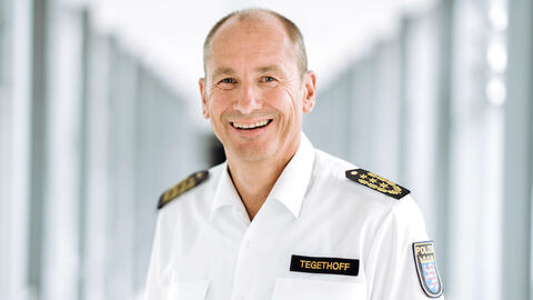 Polizeipräsident in weißem Uniformhemd in einem langen Glasdurchgang