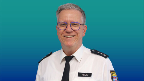 Polizeibeamter mit kurzen grauen Haaren und Brille im weißen Diensthemd mit Krawatte