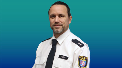 Polizeibeamter mit kurzen schwarzen Haaren und Bart im weißen Diensthemd mit Krawatte