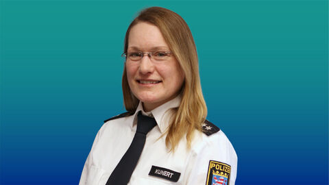 Polizeibeamtin mit hellbraunen langen Haaren und Brille im weißen Diensthemd mit Krawatte