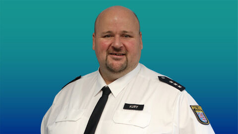 Polizeibeamter mit kurzen Haaren und Bart im weißen Diensthemd mit Krawatte