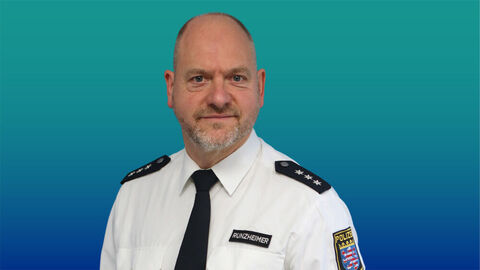 Polizeibeamtin mit sehr kurzen haaren und Bart im weißen Diensthemd mit Krawatte