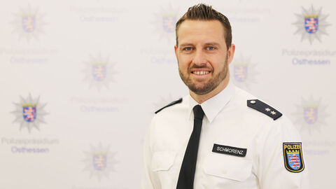 Ein Kollege in weißem Uniformhemd vor der Medienwand mit dem Aufdruck Polizeipräsidium Osthessen