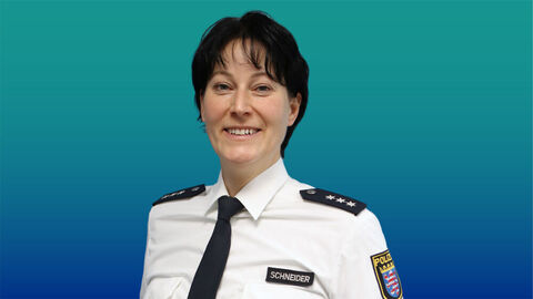 Polizeibeamtin mit kurzen schwarzen Haaren im weißen Diensthemd mit Krawatte