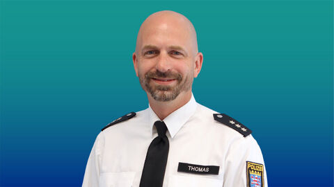 Polizeibeamter mit kurzen Haaren und Bart im weißen Diensthemd mit Krawatte