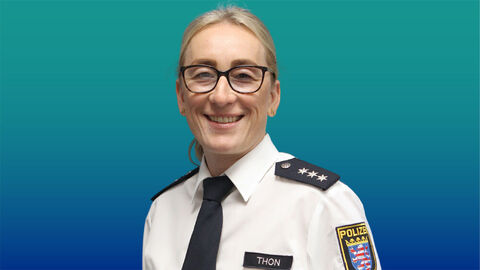 Polizeibeamtin mit langen blonden Haaren und Brille im weißen Diensthemd mit Krawatte