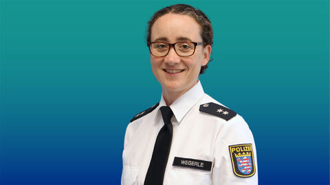 Polizeibeamtin mit dunklen langen Haaren und Brille im weißen Diensthemd mit Krawatte