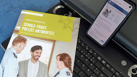 Broschüre auf Rechnertastatur mit Smartphone 