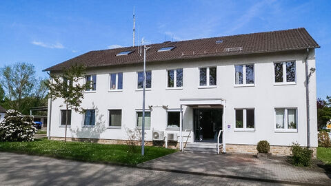 Polizeistation Fritzlar; Foto zeigt das Liegenschaftsgebäude der Polizeistation mit der Zufahrt bei blauem Himmel