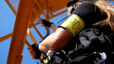 Eine Beamtin der Verhandlungsgruppe klettert auf einen Kran