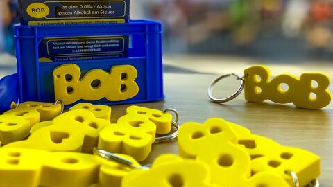 Auf einem Tisch liegen viele BOB-Schlüsselanhänger.