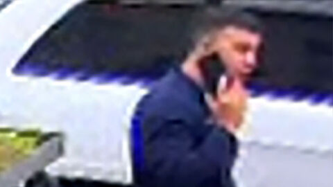 02 Tatverdächtige Person geht mit einem Smartphone telefonierend auf Gehweg