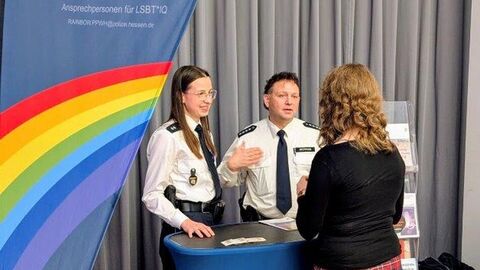 Polizeibeamtin und Polizeibeamter sprechen mit einer Person am Infostand