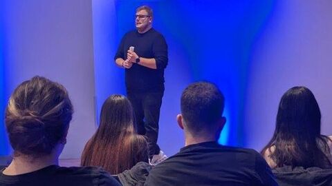 Herr Rühl steht auf der Bühne, davor sitzen Zuschauerinnen und Zuschauer