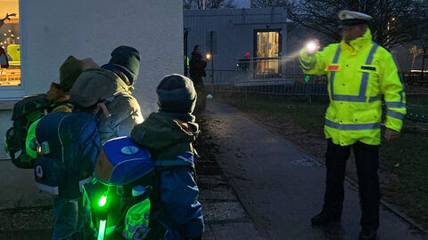 Ein Polizeibeamter klärt Schülerinnen und Schüler über sichtbare Kleidung zur dunklen Jahreszeit auf.