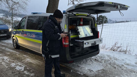 Polizeibeamter steht vor Streifenwagen bei Verkehrskontrolle 