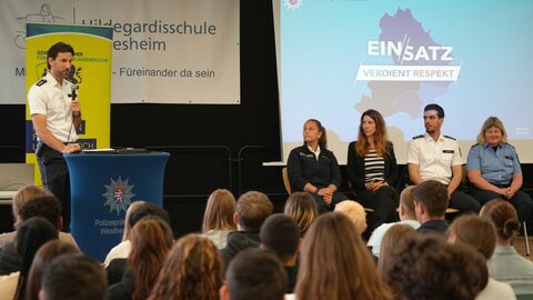 Fünf Polizei- und Kriminalbeamtinnen und -beamte sprechen mit Schülerinnen und Schülern