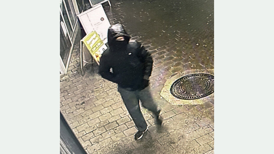 Foto des unbekannten Täters nach bewaffneten Raubüberfall auf Lebensmittelmarkt in Kassel-Waldau; Foto zeigt den Täter von schräg oben auf dem gehweg, bekleidet mit schwarzer Daunenjacke mit Kapuze, einer graue Hose und schwarzen Turnschuhe