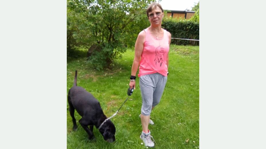 Die Vermisste Frau in Ganzkörperaufnahme. Sie ist 170cm groß, schlank und hat kurze, braune Haare. Auf dem Bild führt sie einen Hund bei sich