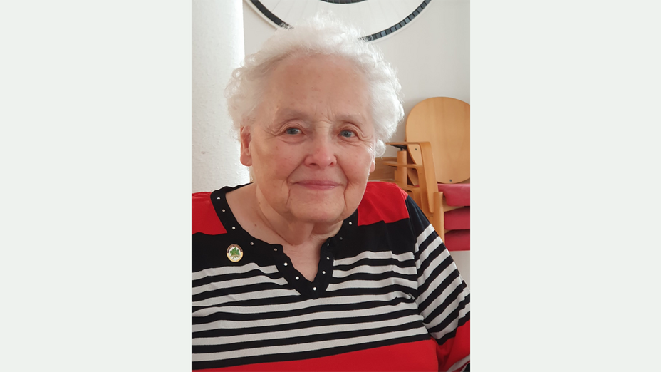 87-jährige Frau mit grauer kurzer Dauerwelle ohne Brille in einem schwarz-weiß gestreiften Pullover mit roten Einsätzen